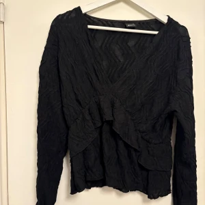 Svart topp med volangdetaljer - Använd fåtal gånger