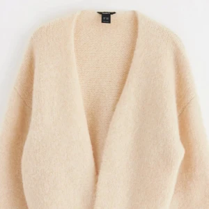 Beige stickad cardigan - Mysig beige stickad kofta i ett mjukt material.Den har en enkel design utan knappar och är i ett löst passande snitt. Ett måste för höst- och vintergarderoben! Helt ny men använd en gång.