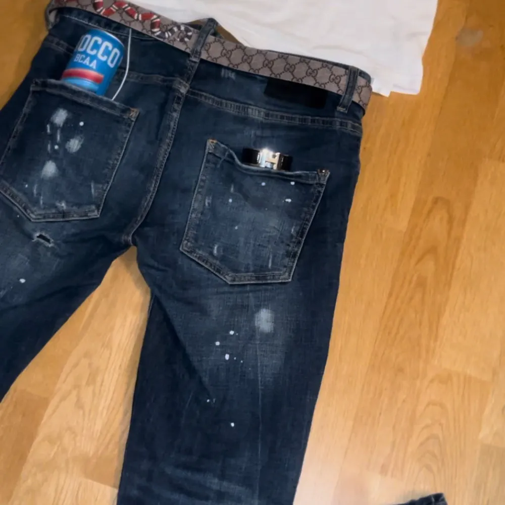 Säljer ett par mörkblå Disquared2 jeans som är bästa jeansen i gamet för grabbarna❤️⭐️med coola slitningar och färgstänk. De har en normal passform och är perfekta för en avslappnad stil. Jeansen har en klassisk femficksdesign och är i bra skick. Perfekta för både vardag och fest!⭐️❤️. Jeans & Byxor.