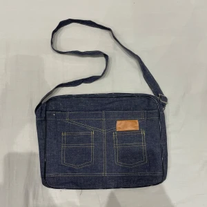 axelväska med fickor💕 - axelväska med två praktiska fickor framtill och en snygg brun detalj. Väskan har en justerbar axelrem och stängs med dragkedja. Rymmer iPad och mindre dator. Bra skick, tyget är dock naturligt tunt så inte så slittålig