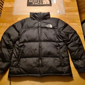 Svart dunjacka från The North Face  - Säljer en svart dunjacka från The North Face i nytt skick. Jackan har en dragkedja framtill och är perfekt för kalla vinterdagar. Den är långärmad och har en normal passform. Perfekt för både vardag och utomhusaktiviteter. Kan förhandla pris såklart men sätter det på 1000 från början. Nypris 2000kr