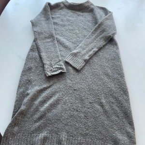 Grå stickad tröja från 157 - Mysig grå stickad tröja från 157 i storlek M. Perfekt för kyliga dagar med sin långa ärmar och ribbade detaljer vid hals och ärmslut. Enkel och stilren design som passar till det mesta. Perfekt för både vardag och mysiga hemmakvällar.