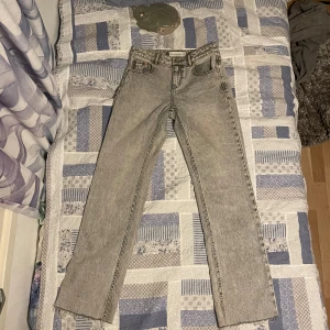 Grå jeansbyxor - Säljer ett par grå jeansbyxor i bra skick. De har en straight passform och är perfekta för både vardag och fest. Byxorna har en klassisk design med fem fickor och knappgylf. Perfekta för höst och vår!