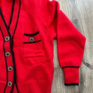 Röd kofta med svarta detaljer - Säljer en snygg röd kofta med svarta detaljer och dekorativa knappar. Den har två fickor fram och ribbstickade muddar. 🖤❤️