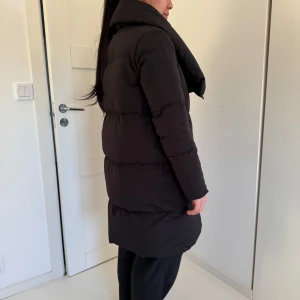 Svart dunjacka från Woolrich - Säljer en supermysig svart dunjacka från Woolrich i storlek XS. Perfekt för kalla vinterdagar med sin tjocka vaddering och långa ärmar. Jackan har en stor krage och stängs med knappar. Den är i mycket bra skick och skulle säga att den passar XS och S. 