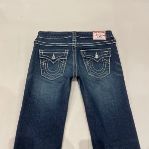 Lågmidjade slim/bootcut jeans från True religion🤩 - Diamanter på knapparna😻Midja: 38 cm rakt över, gren 19 cm o innerben 84 cm💕jae 169 o xs-s som referens o de sitter bra men är åt det tajta hållet! Märkta som W26 men mer åt W25. Obs smutsiga vid hälarna men defenetivt något som lättar lite om man behandlar extra just där efter tvätt. Ersatt knapp på höger ficka (nästan likadan)