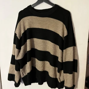 Randig stickad tröja  - Säljer en supermysig randig tröja från 157 i storlek L. Den är svart och beige med breda ränder och har en loose passform. Perfekt för höst och vinter när du vill vara både stilren och bekväm. Tröjan är i bra skick.