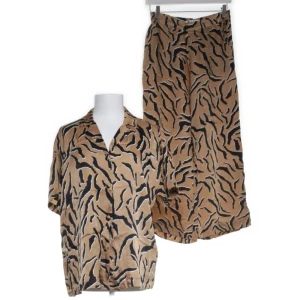 Set byxor & blus från Pulz Jeans - Säljer ett par snygga mönstrade byxor från Pulz Jeans i storlek 36. Byxorna har ett coolt mönster i beige och svart, perfekt för en unik stil. Tillverkade i 100% viskos vilket gör dem superbekväma och lätta. Perfekta för både vardag och fest!