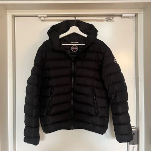 Svart pufferjacka från Colmar - Säljer en snygg svart pufferjacka från Colmar i mycket bra skick. Jackan har en dragkedja framtill och en mysig huva. Perfekt för kyliga höst- och vinterdagar. Den är både stilren och praktisk med sin quiltade design. Passar perfekt för dig som vill hålla värmen med stil! Priset är inte hugget i sten! 