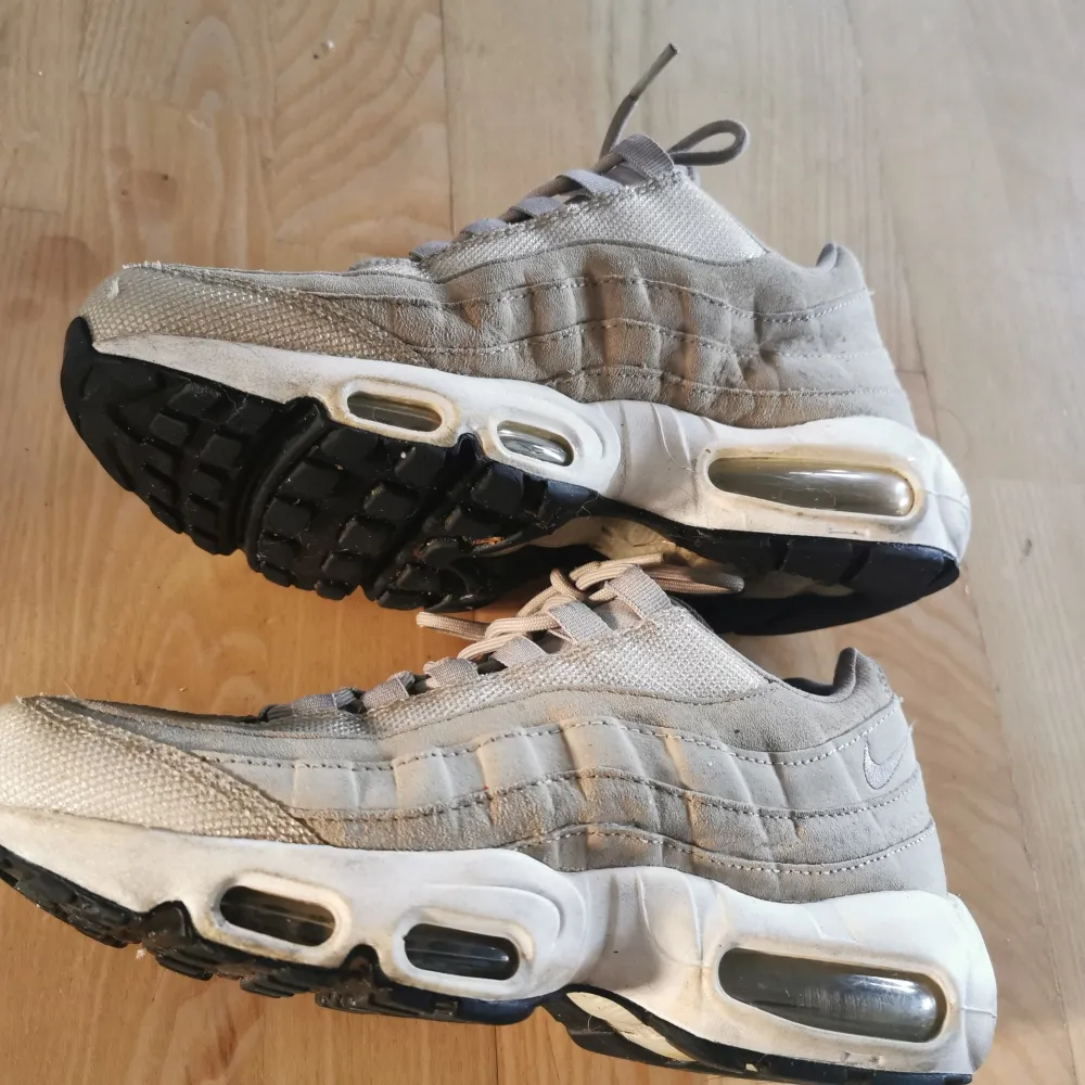 Säljer ett par beige Nike Air Max sneakers i bra skick. De har en klassisk design med synlig luftdämpning i sulan och snörning framtill. Perfekta för både vardag och träning. Lite slitna men fortfarande snygga och bekväma.. Skor.