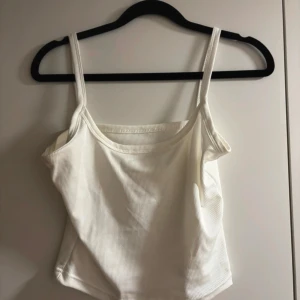 Vit ribbad linnetopp - Säljer en superfin vit ribbad linnetopp i mycket bra skick. Perfekt för sommardagar eller som ett basplagg under en kofta. Toppen har smala axelband och en bekväm passform. Passar till både jeans och kjol!