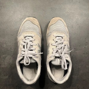 Grå/Beige sneakers från New Balance - Säljer ett par gråa New Balance 373 sneakers i bra skick. De har en klassisk design med snörning och är tillverkade i en kombination av mocka och syntetmaterial. Perfekta för vardagsbruk och ger en skön passform. Storlek 41,5. Nypris 1000kr på New Balance hemsida.