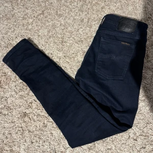Mörkblå jeans från Nudie Jeans - Säljer ett par mörkblå jeans från Nudie Jeans i mycket bra skick. Perfekta för både vardag och fest! 🕺Hör av dig vid minsta lilla intresse, pris kan diskuteras vid snabb affär.
