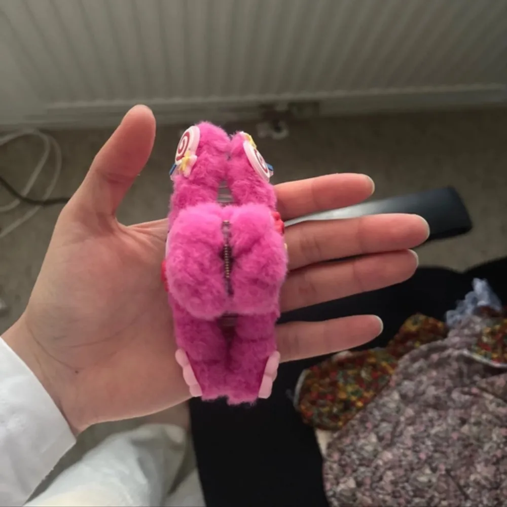 Supergullig rosa hårklämma med fluffigt material och en söt Hello Kitty-dekoration. Klämman har små blommor och en klubba som detalj. Oandvänd. Accessoarer.