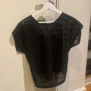 Svart spetsblus - Snygg svart blus i spetsmaterial, perfekt för en kväll ute eller en fest. Den har korta ärmar och ett luftigt, bekvämt snitt. Passar bra till både jeans och kjol för en chic look.