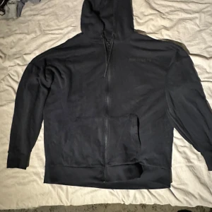 Svart hoodie från MM Sports - Säljer en svart hoodie från MM Sports i storlek L. Den har en dragkedja framtill och en stor logga på ryggen. Perfekt för träning eller en chill dag hemma. Den är i bra skick och superbekväm. Hör av dig om du är intresserad! 🖤