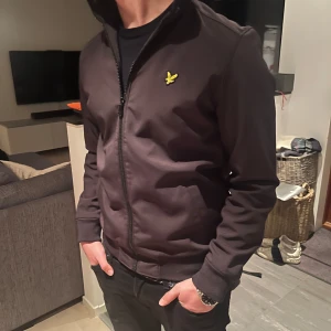 Svart jacka med dragkedja - Säljer en stilren svart softkjell jacka från Lyle & Scott i mycket bra skick. Jackan har inga defekter. Bara att skriva om ni har frågor eller funderingar 
