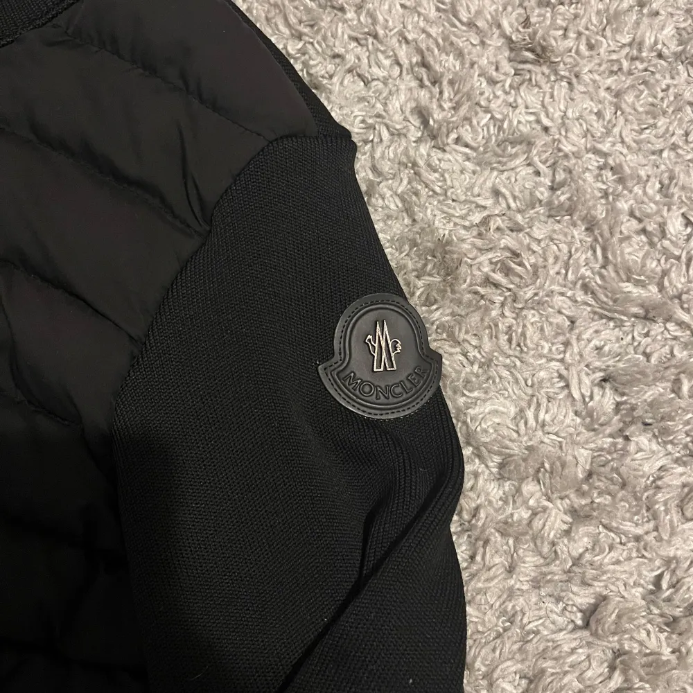 Säljer en snygg svart jacka från Moncler i mycket bra skick. Jackan har en quiltad design på framsidan och långa ärmar. Den är perfekt för höst och vår, med en dragkedja framtill och Moncler-logga på ärmen. Passar både till vardags och lite finare tillfällen.. Jackor.