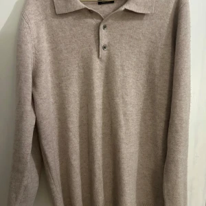 Beige tröja från Massimo Dutti - Säljer en supermjuk och stilren beige tröja från Massimo Dutti. Perfekt för både höst och vinter med sin långa ärmar och klassiska krage med knappar. Tröjan är i mycket bra skick och passar perfekt för en elegant och bekväm look.