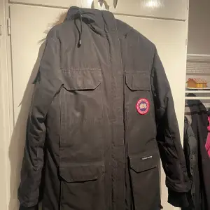 Säljer en svart parkajacka från Canada Goose i mycket bra skick. Jackan har en pälsfodrad huva och är perfekt för kalla vinterdagar. Den har långa ärmar och flera praktiska fickor. Perfekt för dig som vill hålla dig varm och stilren i vinter! ❄️