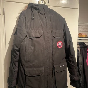 Canada Goose jacka  - Säljer en svart parkajacka från Canada Goose i mycket bra skick. Jackan har en pälsfodrad huva och är perfekt för kalla vinterdagar. Den har långa ärmar och flera praktiska fickor. Perfekt för dig som vill hålla dig varm och stilren i vinter! ❄️