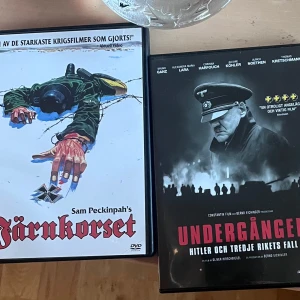 Krigs dvd filmer - Två DVD-filmer: 'Järnkorset' av Sam Peckinpah och 'Undergången: Hitler och tredje rikets fall'. Omslagen visar dramatiska krigsscener och historiska teman.