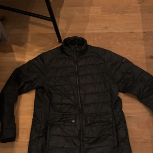  Barbour svart quiltad jacka - Säljer en svart quiltad jacka i bra skick. Den har en dragkedja framtill och långa ärmar. Perfekt för höst och vår när det är lite kyligare ute. Jackan har en stilren design och passar till det mesta. Hör av dig vid intresse!