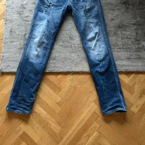 Säljer ett par blå Replay Anbass jeans i bra skick. De har en slim fit passform och är perfekta för vardagsbruk. Jeansen har en klassisk design med fem fickor och en knappgylf. Perfekta för både höst och vår!