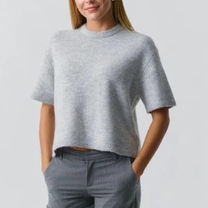 Grå stickad tröja - Säljer en supermjuk och stilren grå stickad tröja med korta ärmar. Perfekt för både vår och höst. Den har en avslappnad passform och är croppad för en modern look. Passar perfekt till både jeans och kjol!