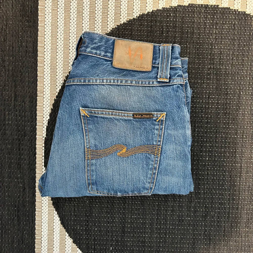 Säljer ett par klassiska blå jeans från Nudie Jeans i storlek 32/32. De har en snygg straight fit och är i bra skick. Perfekta för både vardag och fest! 🕺. Jeans & Byxor.