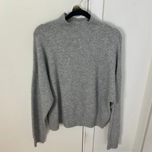 Grå stickad tröja från Gina Tricot - Mysig grå stickad tröja från Gina Tricot i storlek S. Perfekt för kyliga dagar med sin mjuka och bekväma passform. Tröjan har en klassisk design med långa ärmar och ribbade kanter. Ett måste i garderoben för höst och vinter!
