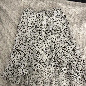 Mönstrad kjol - Kjol med svarta prickar. Volang och dragkedja på sidan. Använd men i bra skick! 