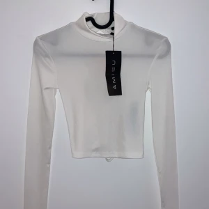 Vit långärmad topp från Amisu - Säljer en snygg vit långärmad topp från Amisu i nytt skick. Den har en cool snörning i ryggen som ger en unik look. Perfekt för både vardag och fest! ✨