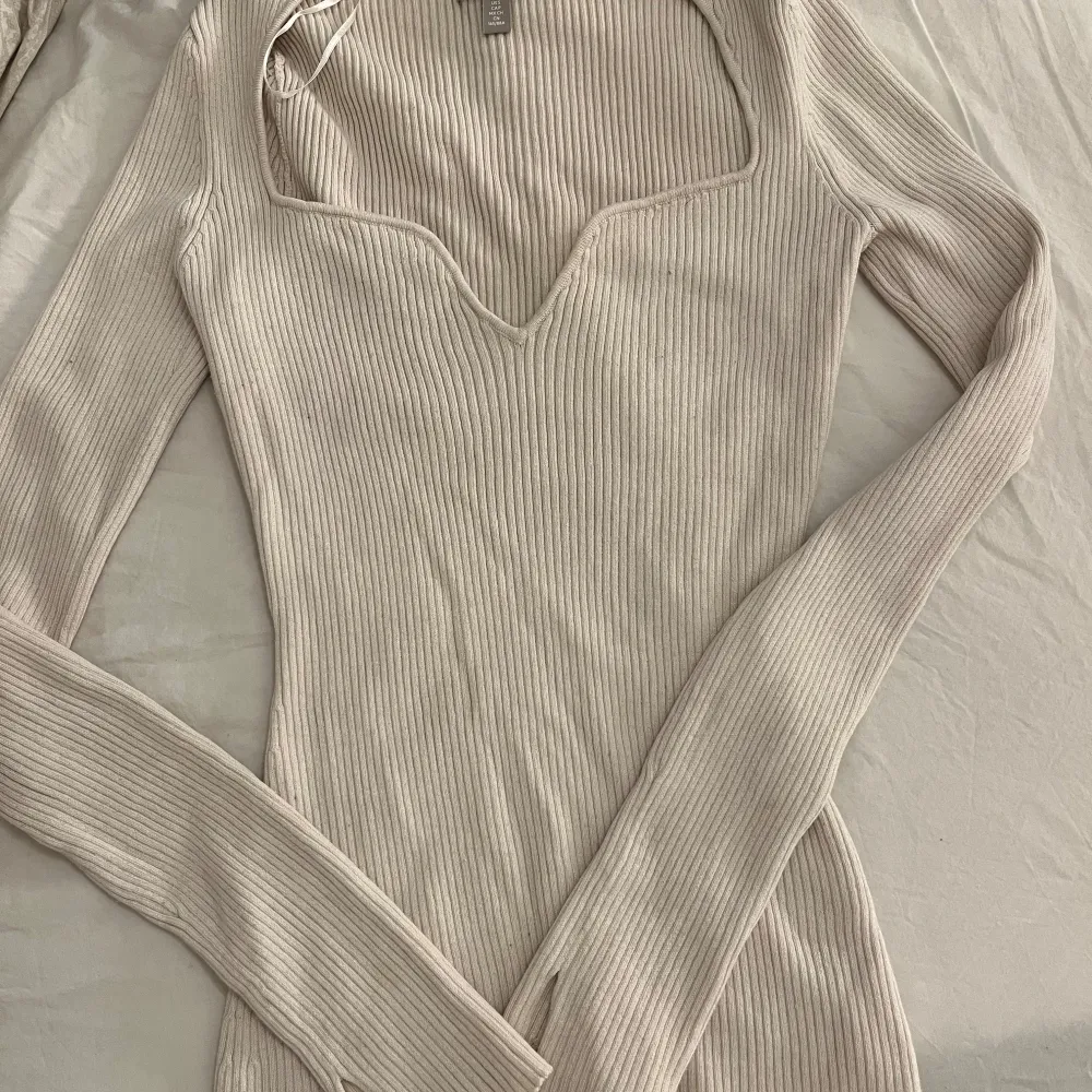 Säljer en superfin beige ribbad tröja från H&M. Den har en snygg v-ringning och långa armar.  Tröjan är i mycket bra skick! Skicka ett meddelande vid intresse! Passar både S och M . Tröjor & Koftor.