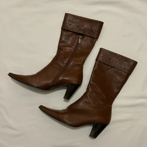 Bruna boots med klack och mönstrad kant - Snygga bruna stövletter/boots. Passar perfekt till fest eller utgång. Har en mönstrad kant upptill (bild 2). Storlek 39/40. Klacken är ca 6 centimeter. 