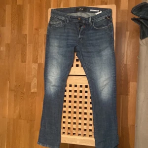Blå jeansbyxor - Säljer ett par snygga blå jeans i bra skick från replay. De har en klassisk femficksdesign med knapp och dragkedja framtill. Perfekta för vardagsbruk och kan enkelt matchas med olika outfits. Pris kan diskuteras 