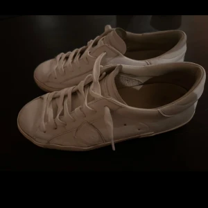 Vita sneakers från Philippe Model - Säljer ett par stilrena vita sneakers från Philippe Model. De är i skinn och har klassisk snörning. Perfekta för både vardag och festliga tillfällen. Skorna är i bra skick med en tidlös design som passar till det mesta. 