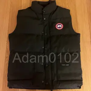 Canada Goose Dunväst - Svart. Säljer en klassisk Canada Goose väst i svart färg. Västen är i mycket gott skick och passar perfekt för kalla dagar när du vill hålla värmen utan att behöva bära en jacka.  Detaljer: 	•	Färg: Svart 	•	Material: Yttertyg i slitstarkt material med högkvalitativ dunfyllning för maximal värmeisolering 	•	Storlek: [L] 	Original med den ikoniska Canada Goose-loggan på bröstet 	Denna väst är både stilren och funktionell – idealisk för höst- och vinterbruk.  Pris: [2000]