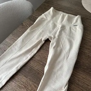 Leggings i ny skick, endast använda 2 gånger. De är högmidjade och har en tight passform, perfekt för både träning och vardag. Materialet är mjukt och stretchigt, vilket gör dem superbekväma att ha på sig. Kräm vita i färgen. Stl M men passar bra för någon med S med. 