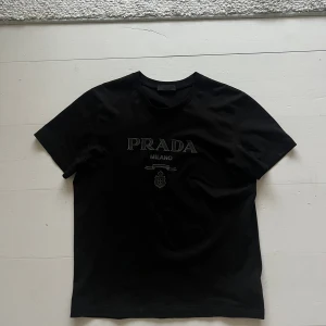 Prada T-Shirt - Säljer nu denna fina Prada t-shirt i storlek s, inköpt på Vestiaire i nyskick och bara använts ett par gånger.