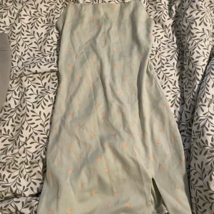 Blommig klänning kort klänning. - En mint färgad, kort, blommig klänning med dragkedja i ryggen och sluta vid låret från BikBok i storlek XS. Klänningen har bara användas en gång och säljs på grund av att den inte kommer till användning längre. 
