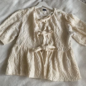 Beige blus med knytning - Säljer en superfin beige blus med trekvartsärm och knytning framtill. Den har en härlig textur och en luftig passform som är perfekt för all möjliga tillfällen . Blusen är i nyskick och passar både till vardags och festligare tillfällen.🫶🏼