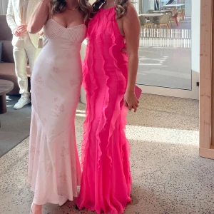 Klänning med volanger - Cerise-rosa klänning med volanger. Storlek 38, men funkar om du är en storlek 36 då man kan anpassa banden. Köpt från Asos för cirka 1100kr, använd en gång.