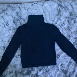 Svart polotröja från H&M - Säljer en stilren navy polotröja från H&M:s Divided-kollektion. Tröjan är i storlek S och har långa ärmar. Perfekt för höst och vinter, och den är gjord i ett mjukt bomullsmaterial som håller dig varm och bekväm. Passar både till vardags och lite fin