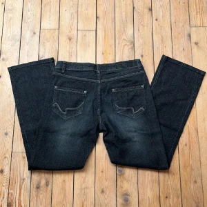 Svarta jeans med bootcut - Säljer ett par snygga mörkblå jeans med bootcut. De har en klassisk femficksdesign och är i ett stretchiga denimtyg. Perfekta för både vardag och fest!