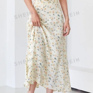 Blommig långkjol från SHEIN - Säljer en superfin långkjol från SHEIN med ett gulligt blommönster i gult och grönt på en krämvit bakgrund. Kjolen har en elegant passform och är perfekt för vår och sommar. Den har en diskret dragkedja i sidan för enkel påklädning. Perfekt för en dag på stan eller en sommarfest! 🌼