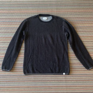 Mörkblå stickad tröja från Shine Original - Säljer en snygg svart/grå stickad tröja från Shine Original. Den har ett diskret mönster och är perfekt för både höst och vinter. Tröjan är långärmad och i storlek Large. Perfekt för att hålla sig varm och stilren!