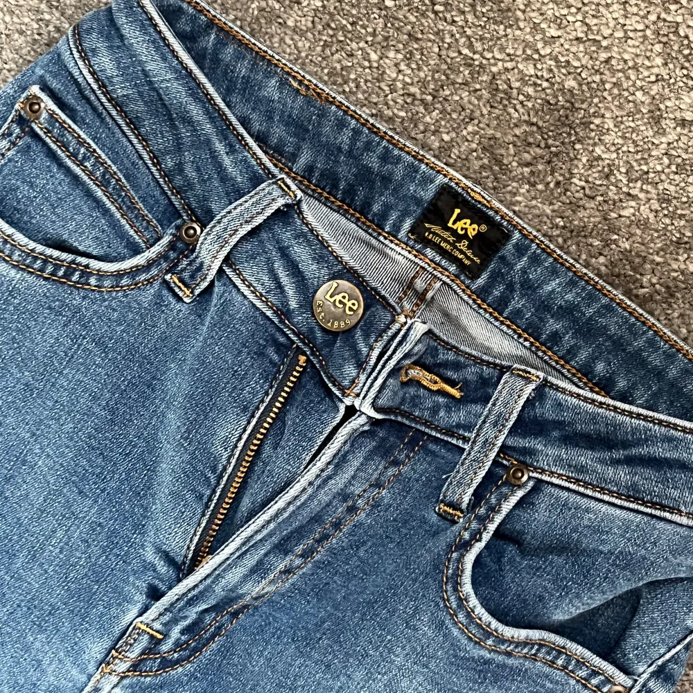 Säljer ett par klassiska blå jeans från Lee. De har en snygg slim passform som sitter bra på alla ställen. De har länge varit mina favoriter. Jeansen har en dragkedja och knapp framtill samt fyra fickor. Jag är ca 170 cm lång.. Jeans & Byxor.