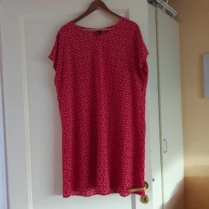 Röd kortklänning med prickigt mönster - Säljer en söt röd kortklänning med vita prickar. Klänningen har en avslappnad passform och korta ärmar, perfekt för sommarens fester eller en avslappnad dag ute. Materialet känns lätt och luftigt, vilket gör den idealisk för varma dagar. Ett måste i garderoben för den som älskar prickiga mönster!
