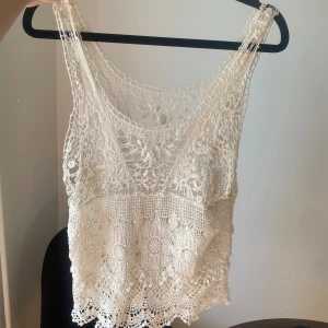 Vit spetslinne - Säljer ett superfint vitt spetslinne som är perfekt för sommaren. Det är ärmlöst och har ett vackert virkat mönster som ger en romantisk känsla. Passar perfekt till både vardag och fest!